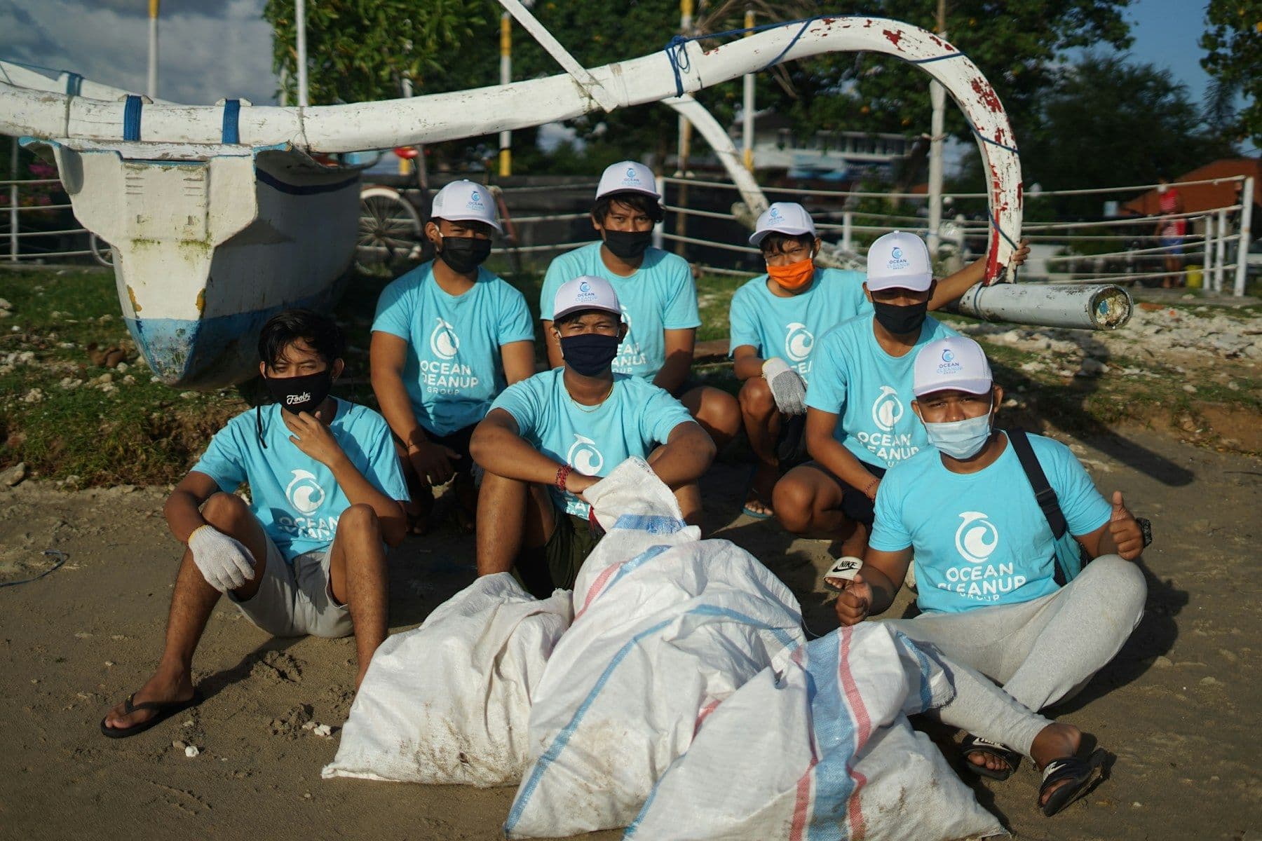 A cleanup crew in matching shirts resting beside full bags of collected litter