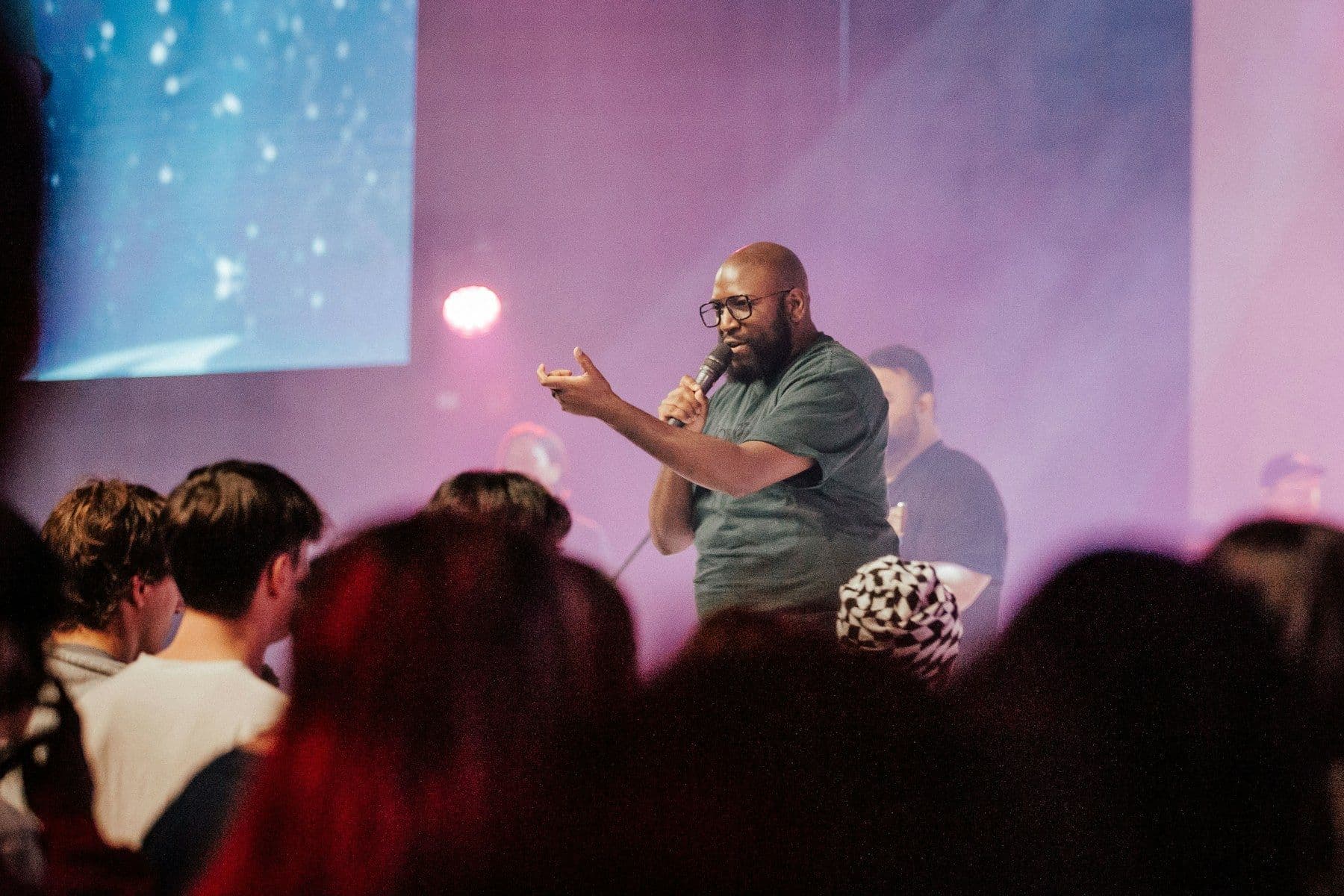 A worship leader speaking into a microphone to a gathered congregation