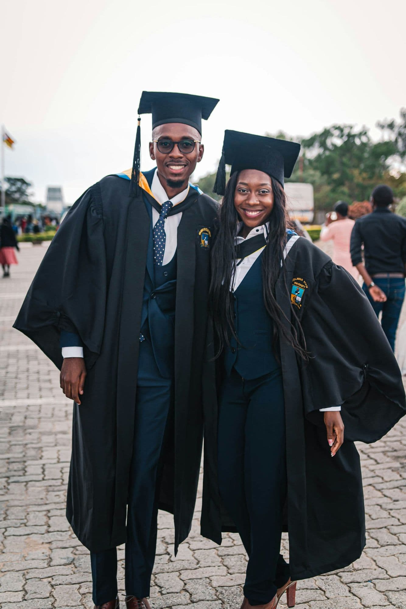 Two graduates in caps and gowns smiling together