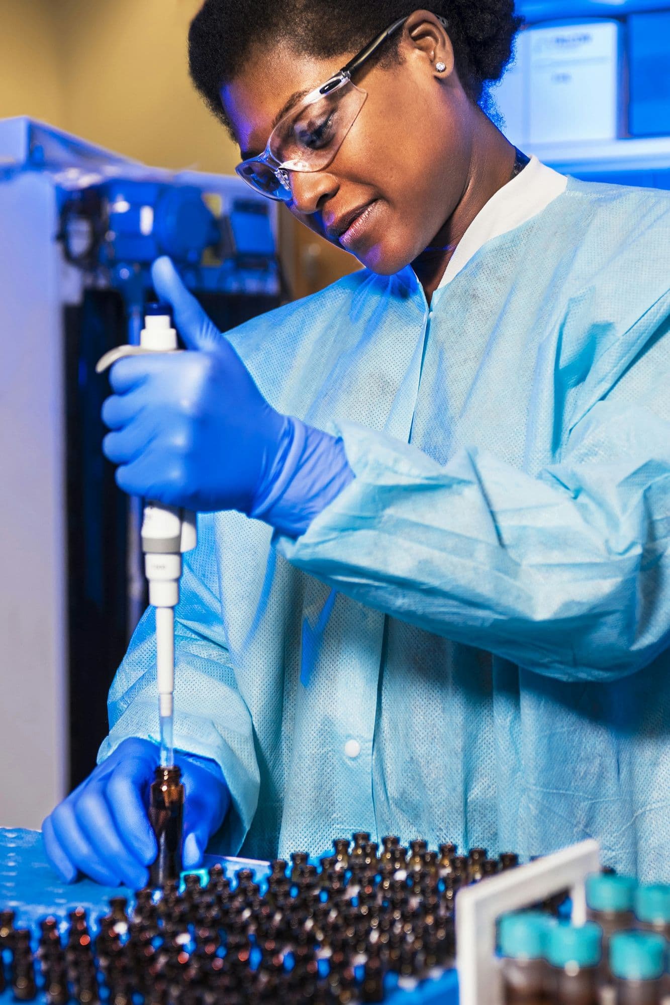 A scientist in blue protective gear handling water sample vials