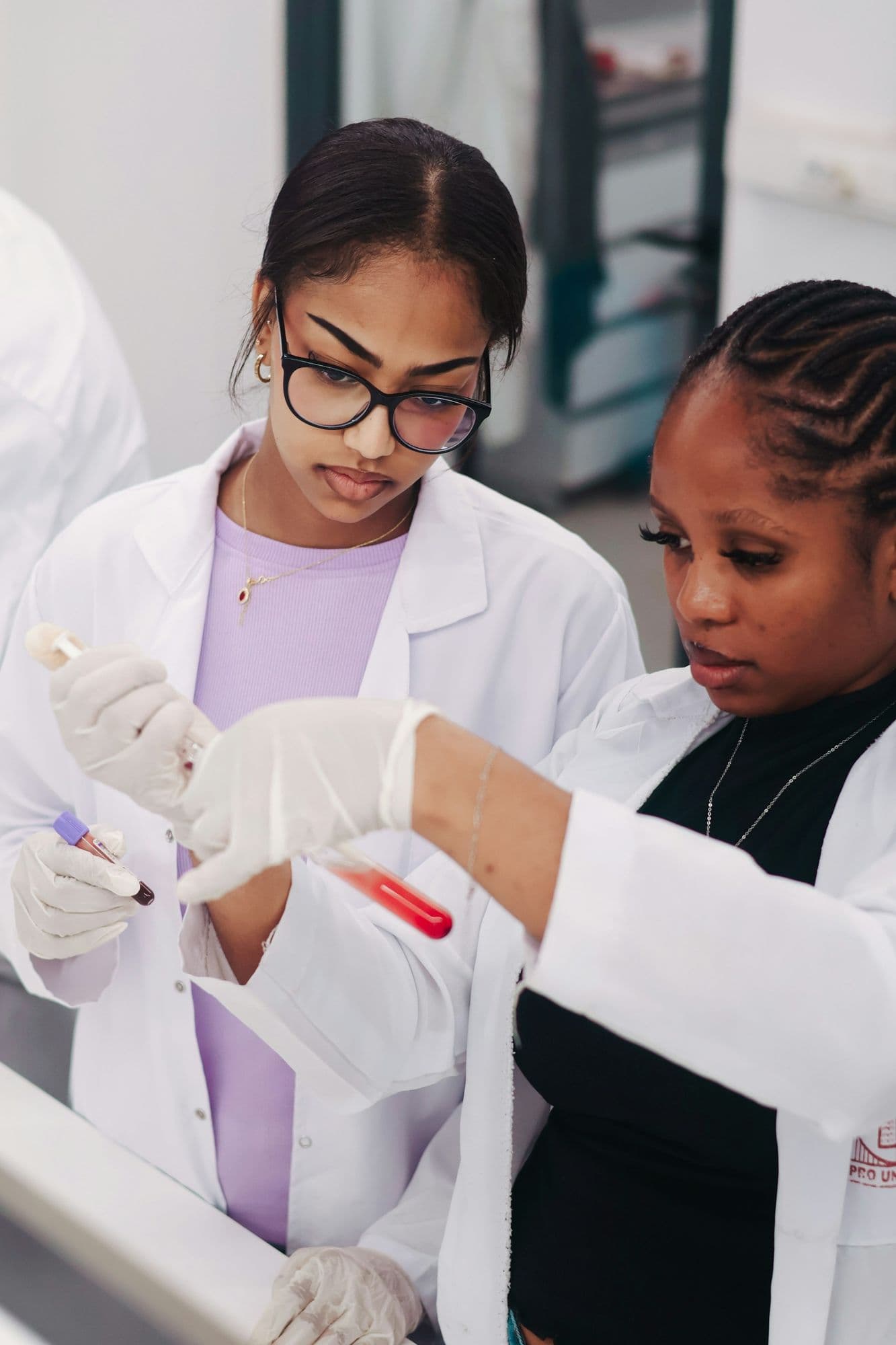 Two young women scientists in lab coats working with samples